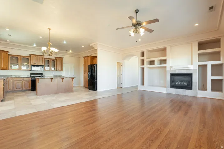 Wood-finish flooring, built-in shelving, tile fireplace surround, tile flooring, and a kitchen island with cabinetry