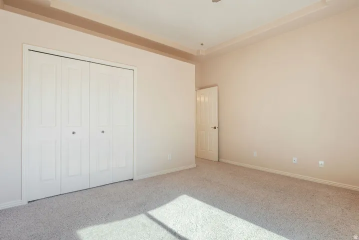 Recessed ceiling detail, light-toned carpeting, and a bi-fold closet
