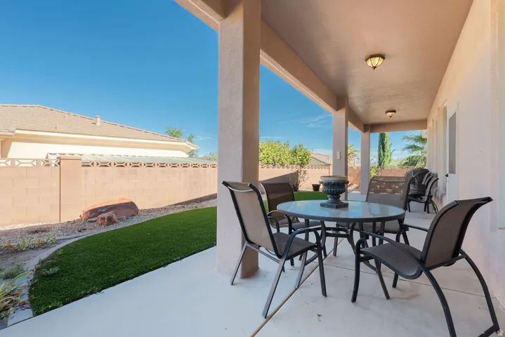 Covered patio with integrated lighting, concrete flooring, and a manicured lawn