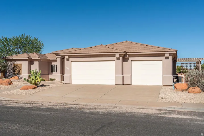 Stucco exterior with a tile roof, two-car garage, and desert landscaping