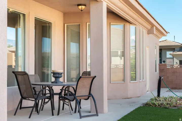 Covered patio with a stucco exterior, multiple large windows, and a built-in outdoor light fixture