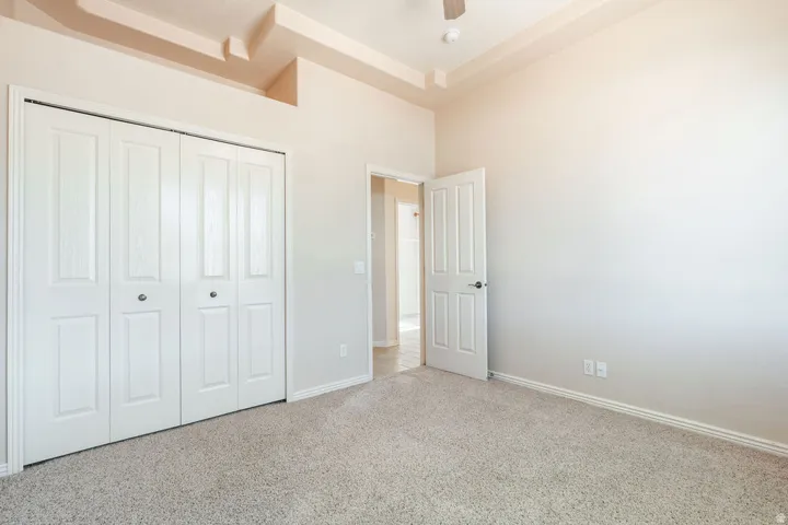 Tray ceiling, recessed lighting, neutral carpet, white paneled doors, and bi-fold closet doors