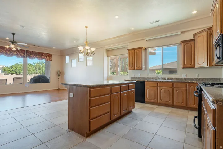 Kitchen island with stone countertop, wood-finish cabinetry, tile flooring, and a ceiling fan
