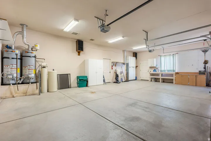Spacious garage with multiple water heaters, built-in workbench, and overhead lighting