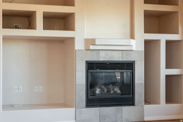 Built-in media center with shelving, recessed compartments, and a fireplace featuring a tiled surround and hearth