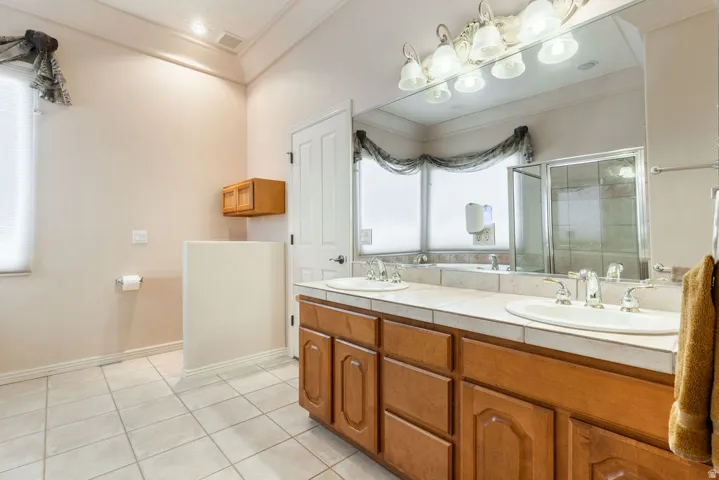 Dual vanity with undermount sinks, wood-finish cabinetry, and a tile countertop
