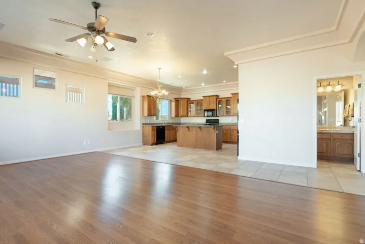 Wood-finish flooring, ceiling fan with integrated lighting, recessed lighting, kitchen with wood cabinetry, and tile flooring