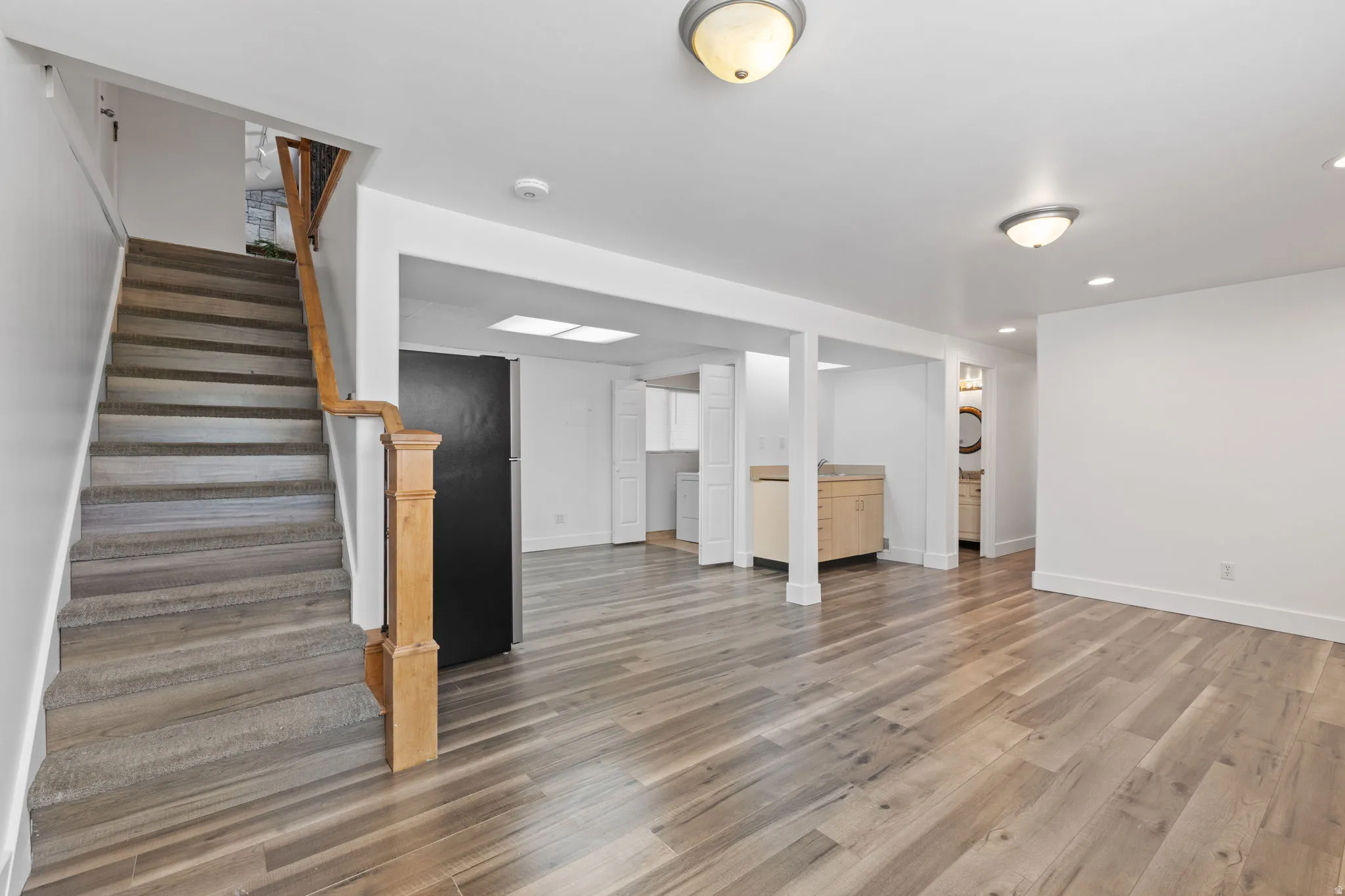 Wood-finish flooring throughout, bright recessed lighting, and a neutral color palette