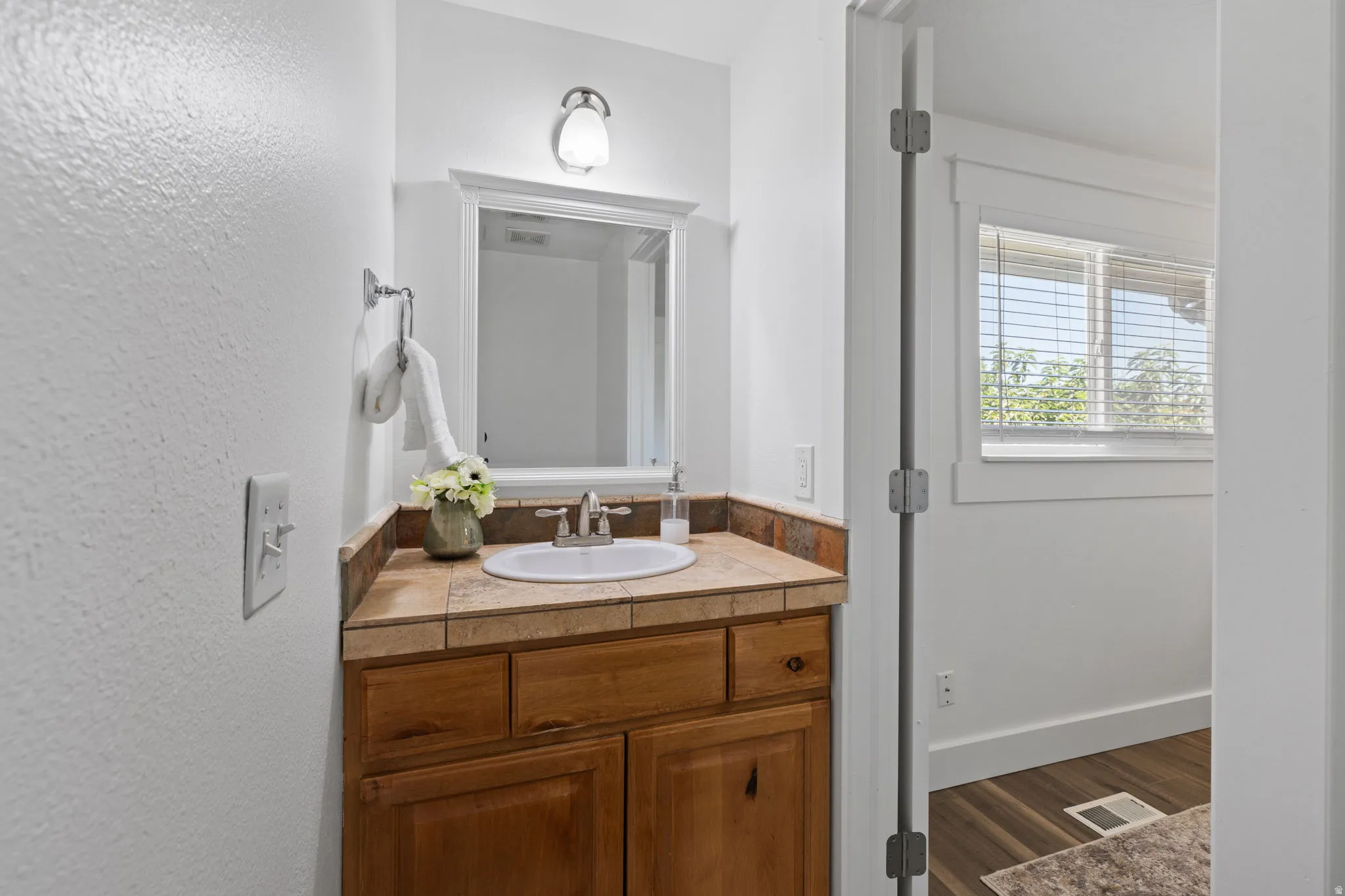 Wood-finish vanity cabinetry with a tiled countertop and integrated sink