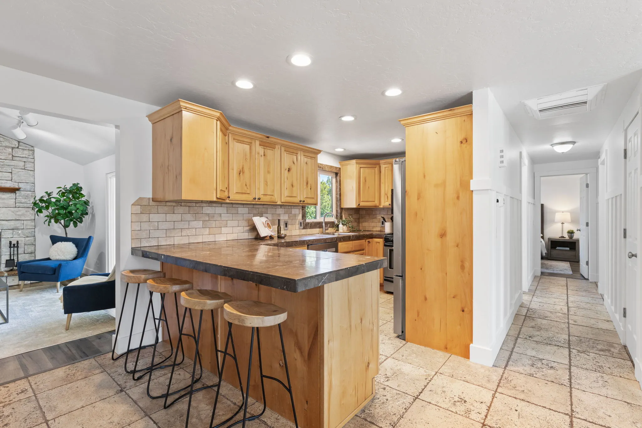 Kitchen island with integrated bar seating, wood cabinetry, tile backsplash, and stainless steel appliances