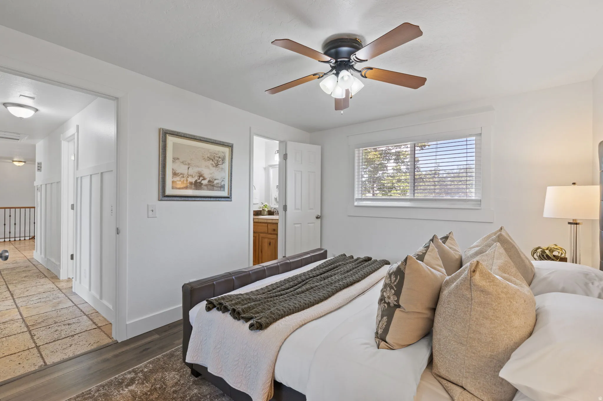 Wood-finish flooring, ceiling fan with integrated lighting, window with blinds, paneling, and an adjacent hall with tile flooring