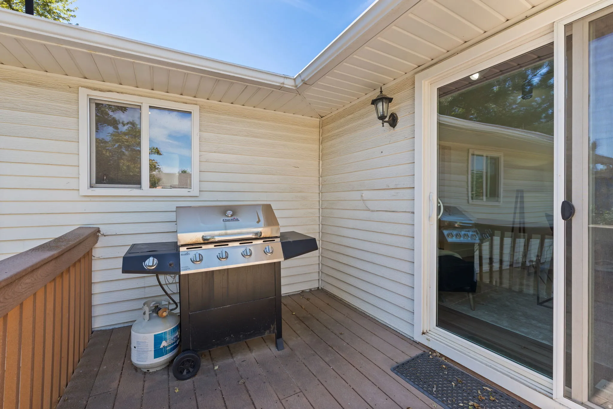 Outdoor deck area featuring a sliding glass door and an exterior wall light fixture