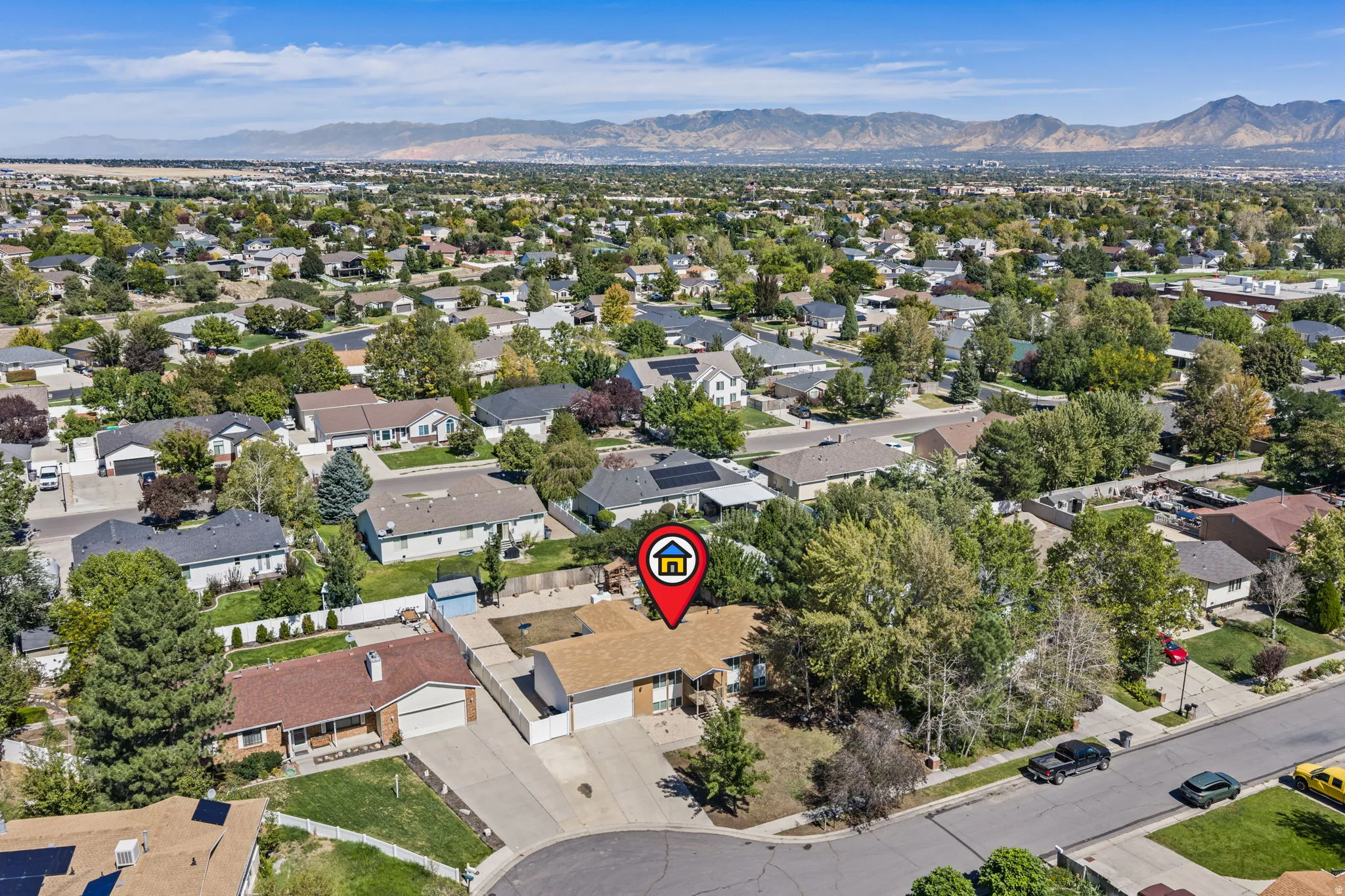 Residential property with an attached garage, a paved driveway, and mature landscaping
