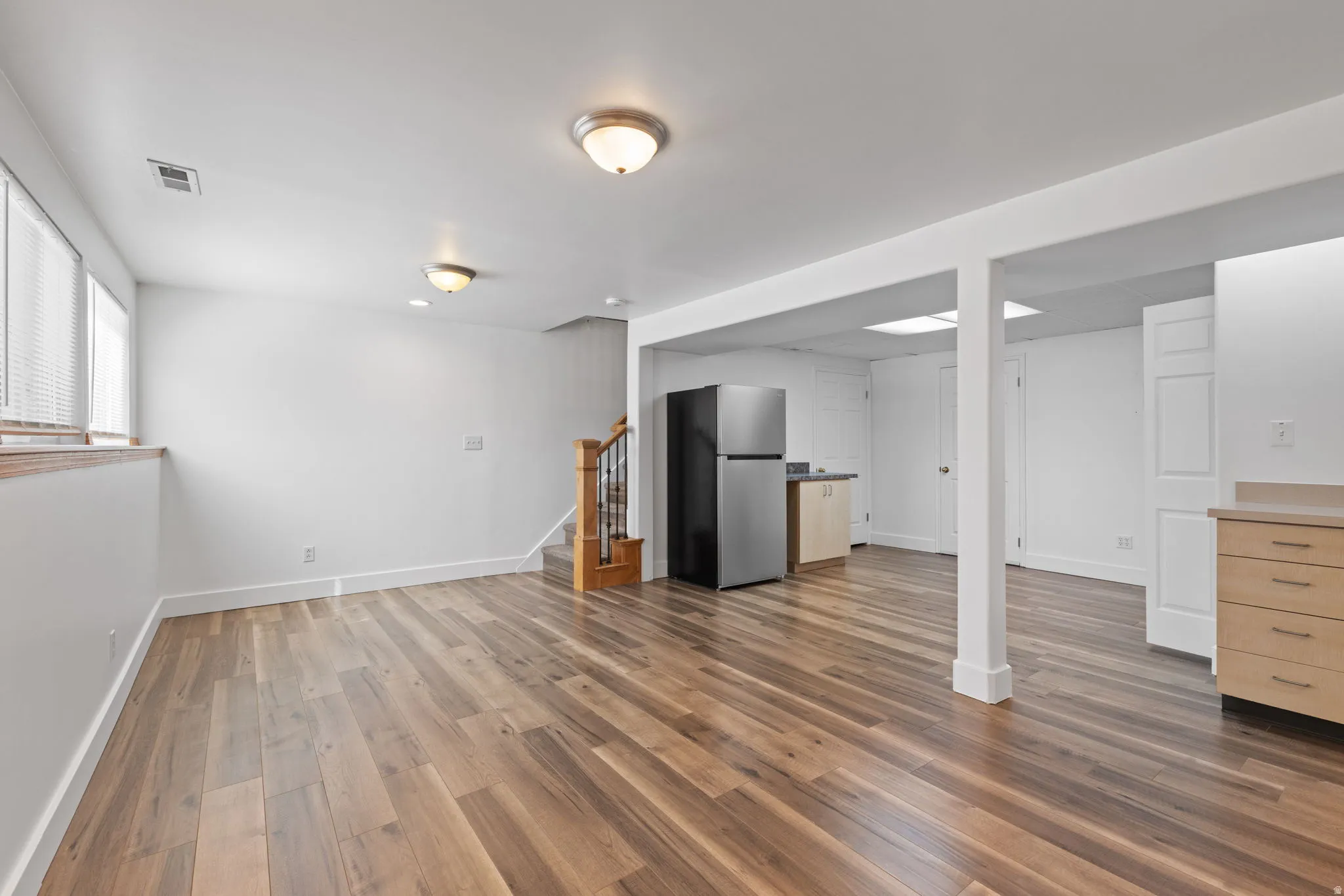 Open-concept living space featuring wood-finish flooring, recessed lighting, and a built-in kitchenette with a refrigerator