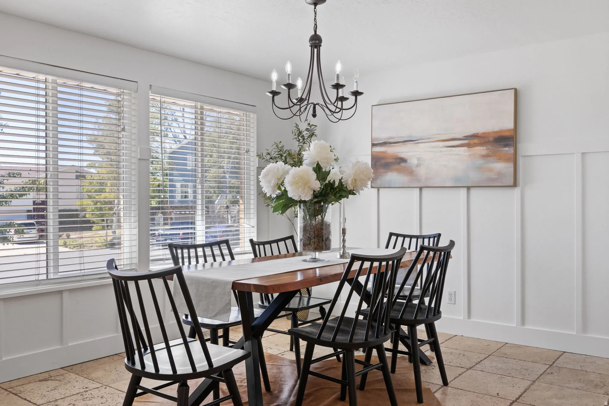 Rectangular windows with horizontal blinds, board and batten wall accent, chandelier lighting, and tile flooring