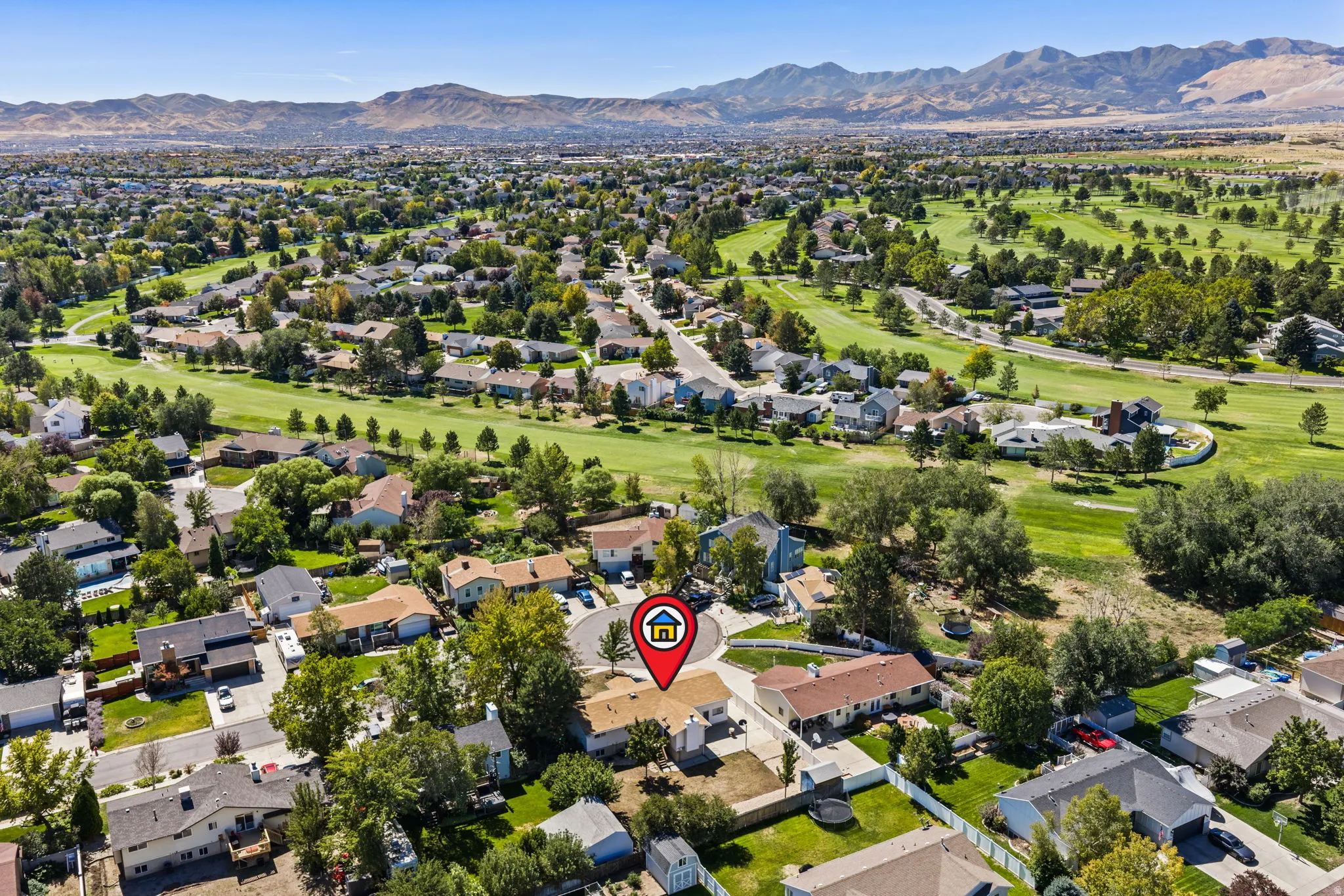 Expansive residential area with mature trees, green spaces, and distant mountains