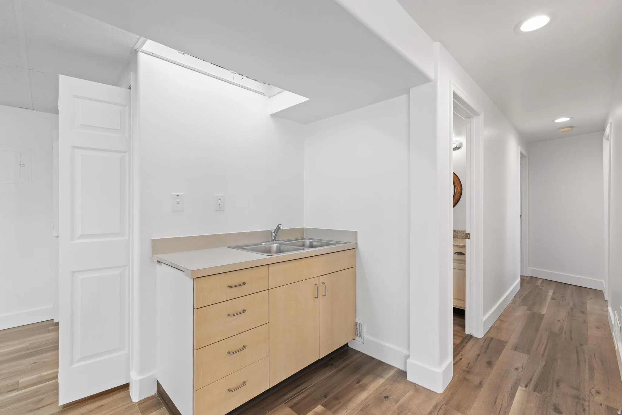 Laundry area with light wood-finish cabinetry, a double basin sink, and laminate countertop