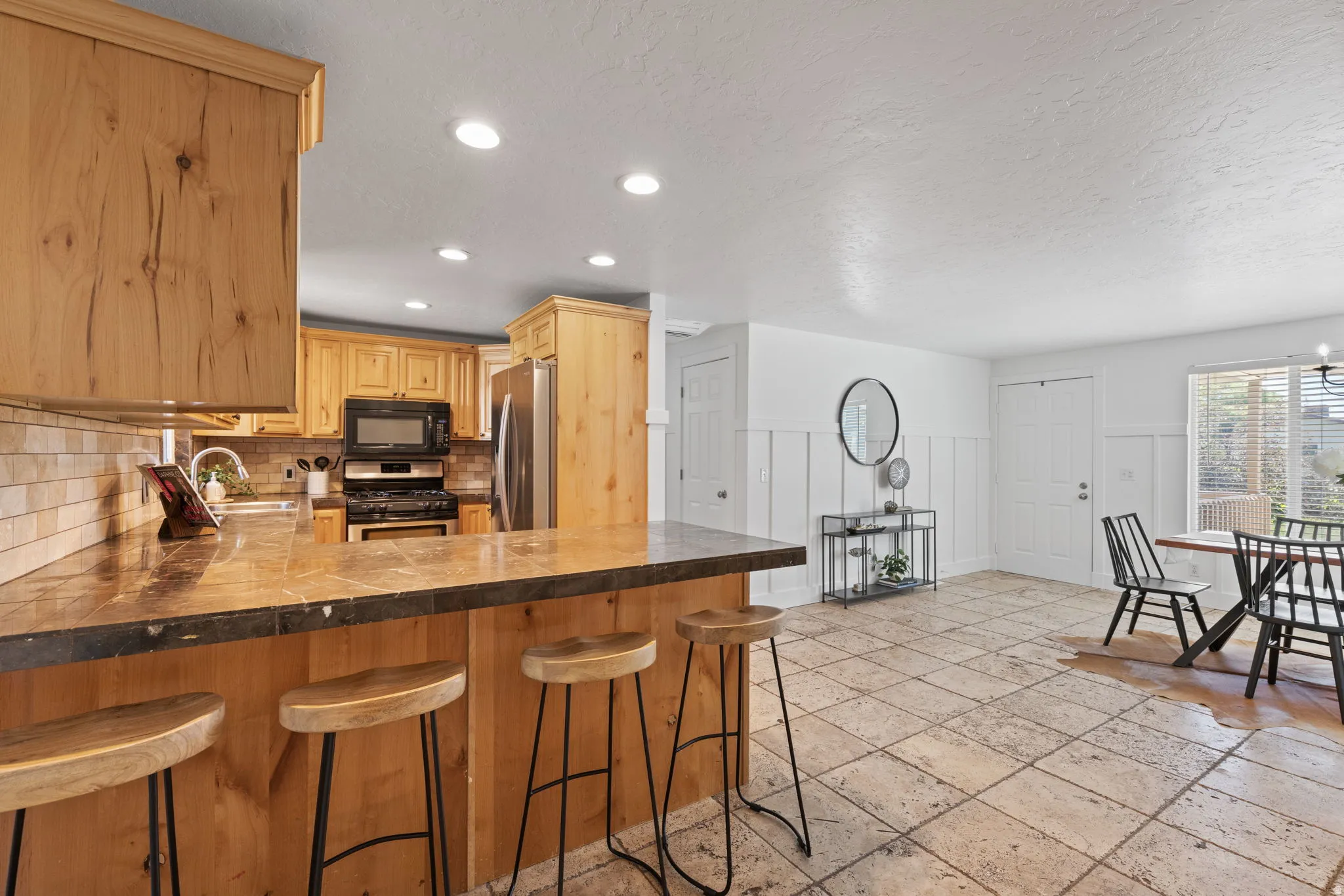 Natural wood cabinetry and a tiled backsplash complement the kitchen's integrated appliances