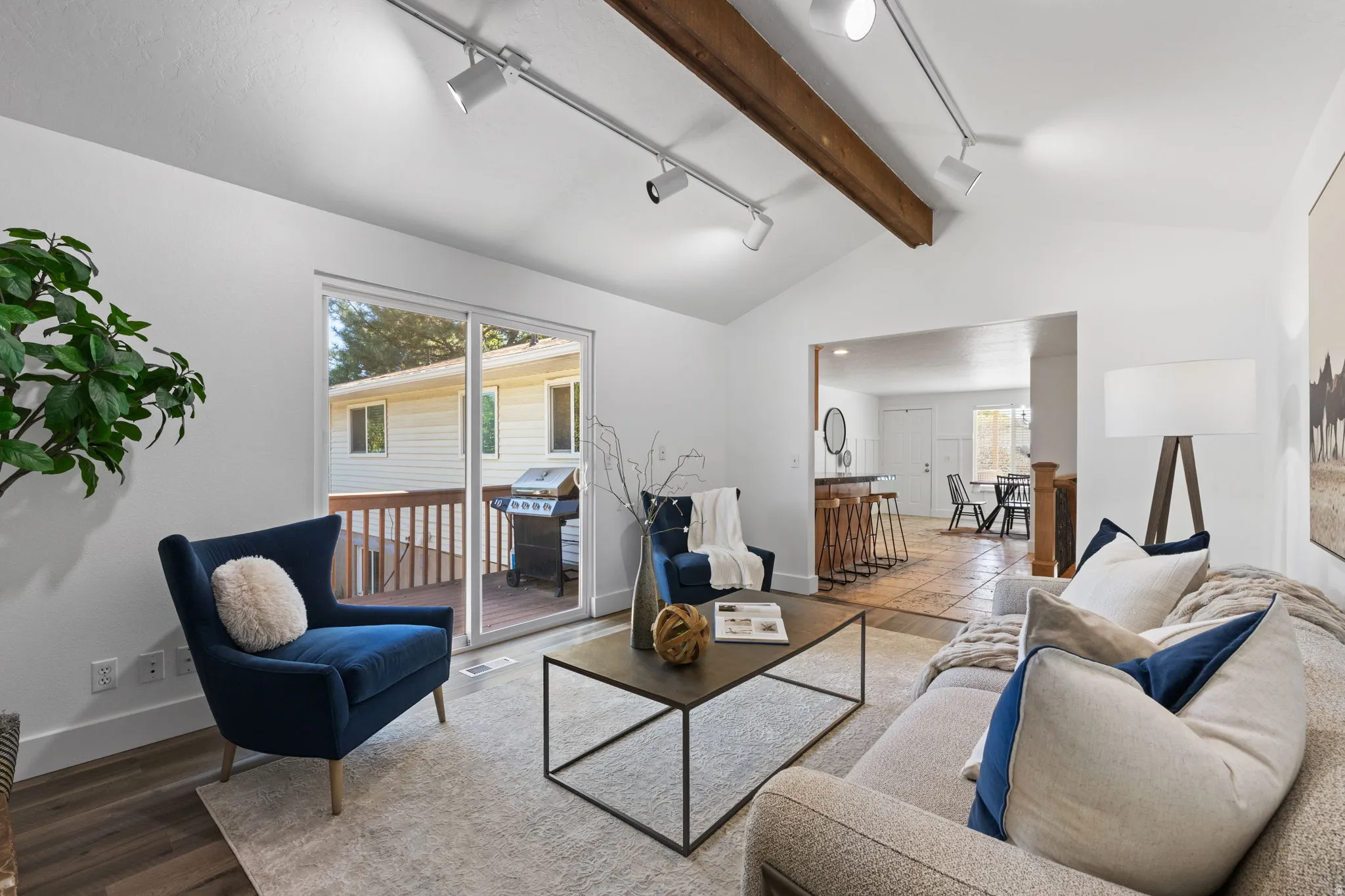 Vaulted ceiling with exposed wood beam, track lighting, and wood-finish flooring