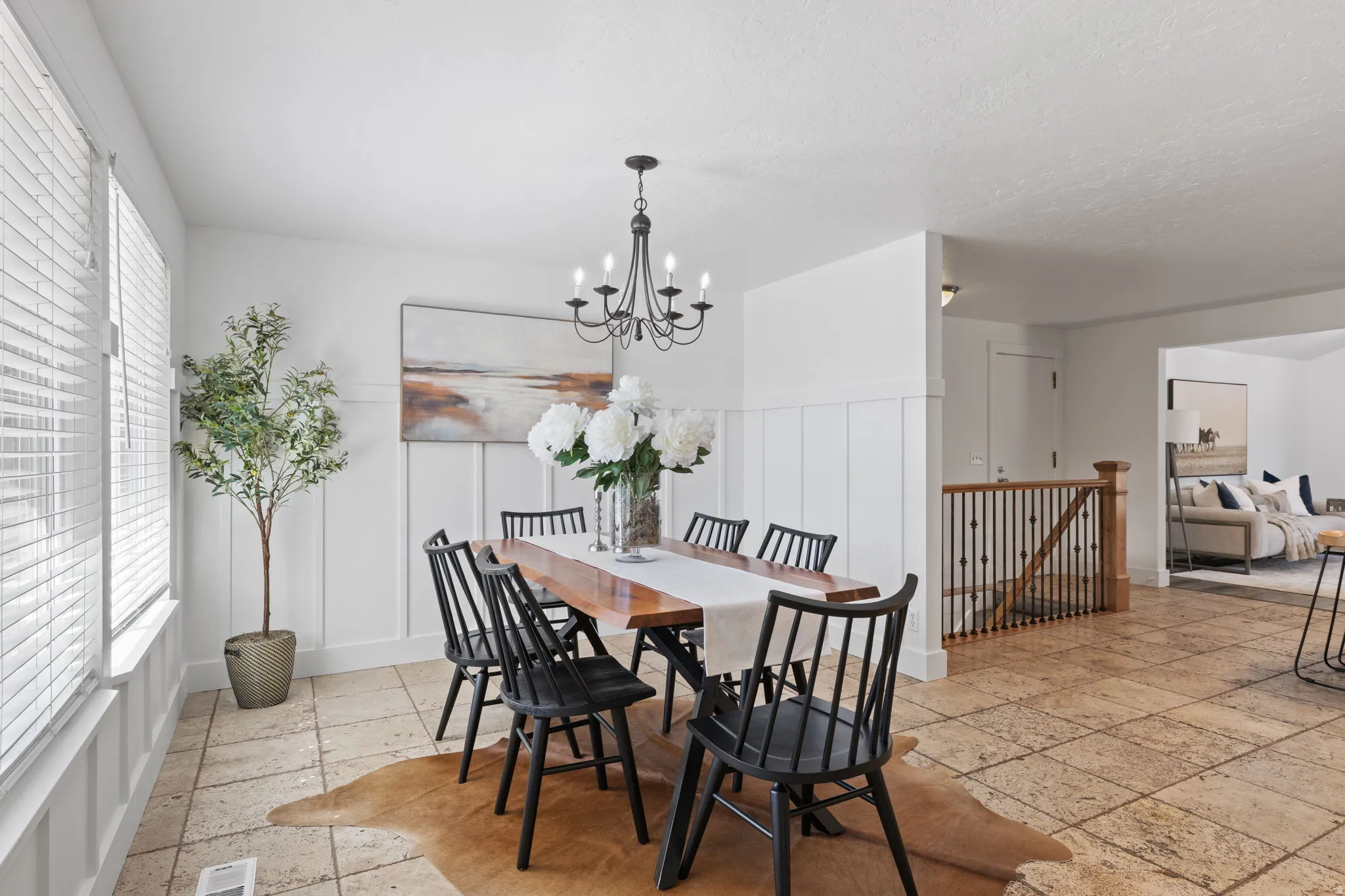 Dining area featuring stone tile flooring, board and batten wall paneling, and a black wrought iron chandelier