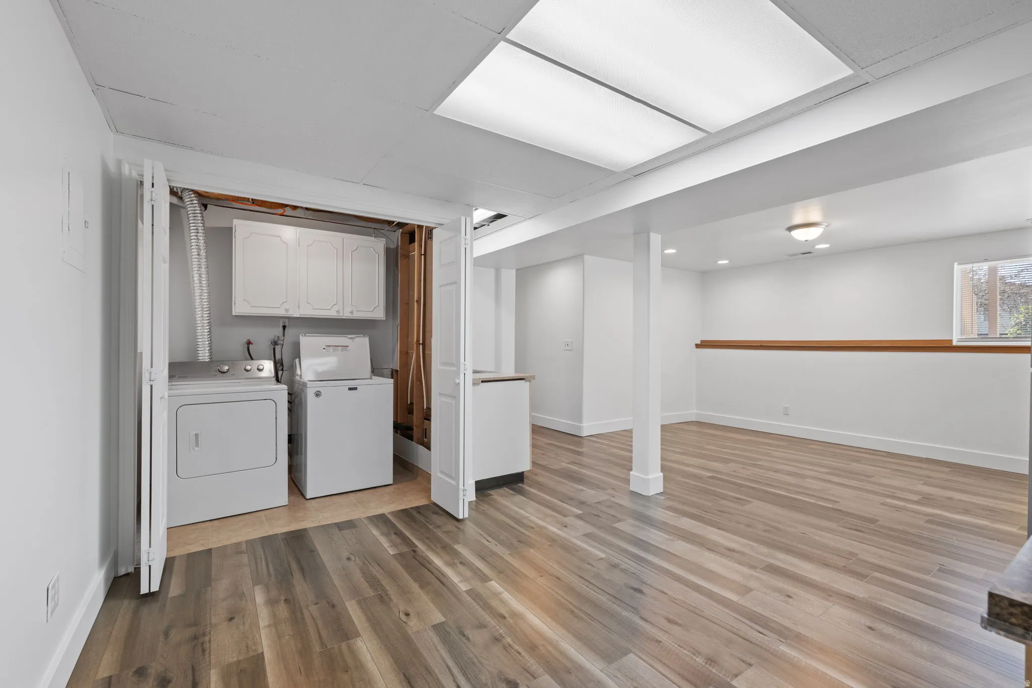 Laundry area with built-in cabinetry, wood-finish flooring, recessed lighting, and a light-toned wood accent wall