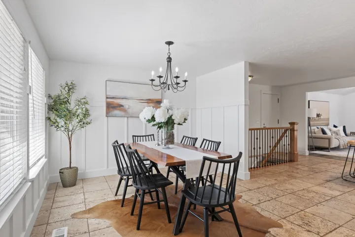 Dining area featuring stone tile flooring, board and batten wall paneling, and a black wrought iron chandelier