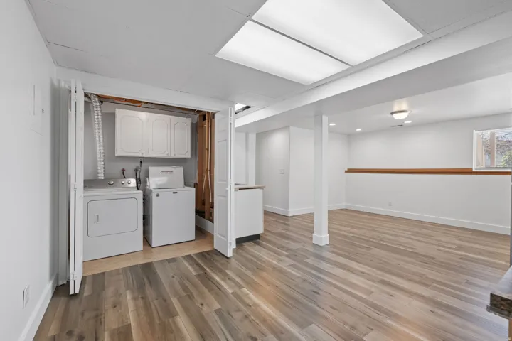 Laundry area with built-in cabinetry, wood-finish flooring, recessed lighting, and a light-toned wood accent wall