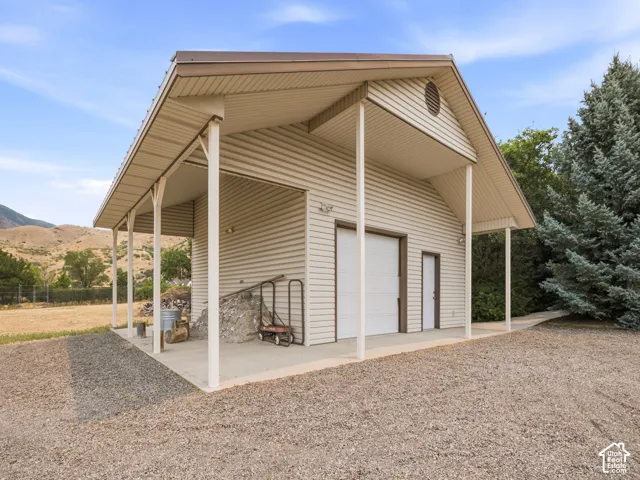 Detached outbuilding with a covered awning, two garage bays, and an additional exterior door