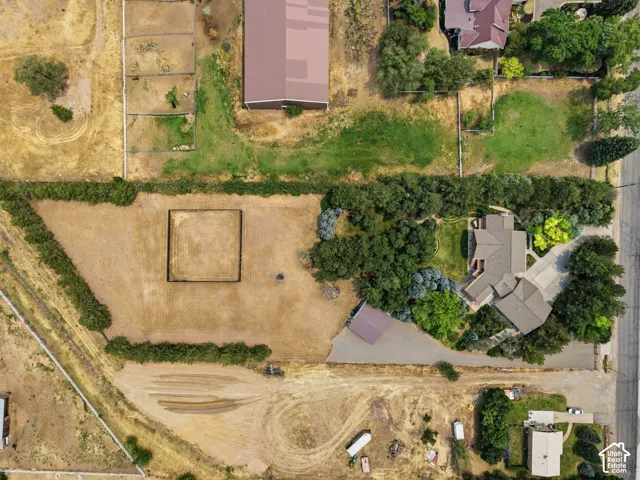 Expansive property featuring a multi-wing residence, mature tree coverage, and an unpaved lot with a fenced enclosure