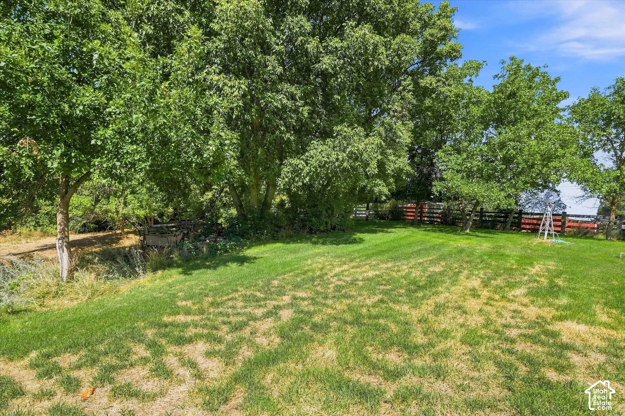 Expansive green lawn with mature trees and a wooden fence