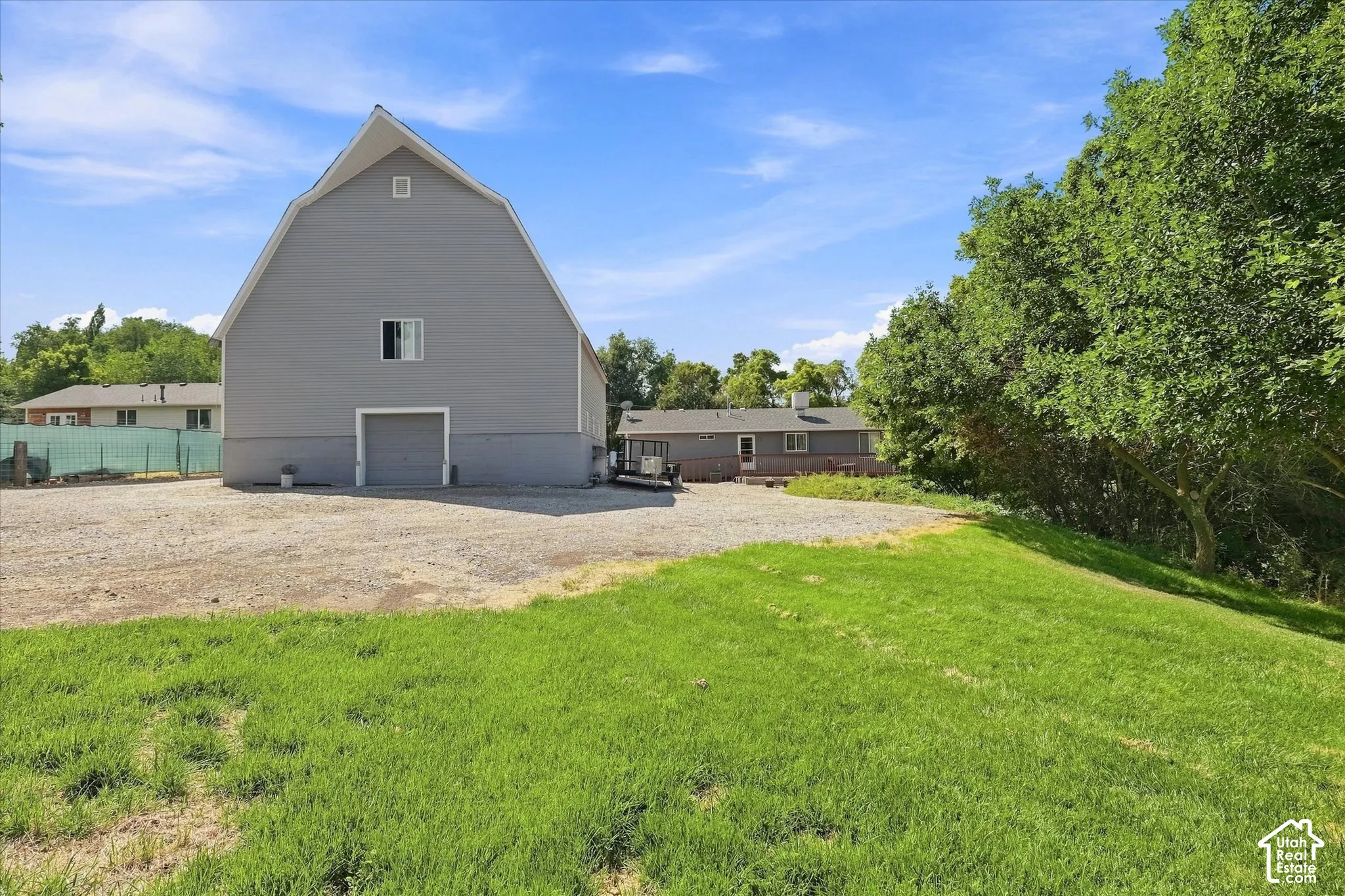 Gabled gray barn structure with a window and a garage door