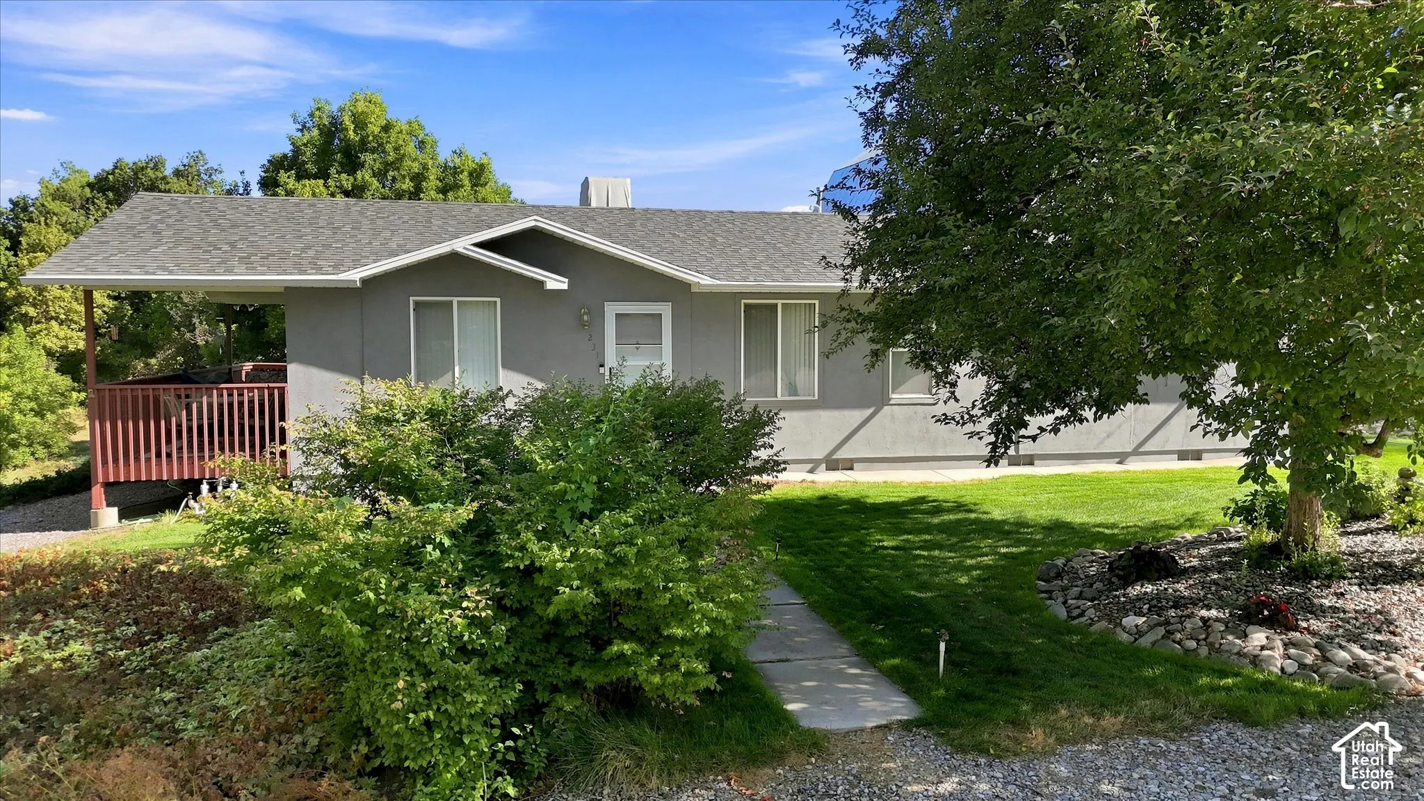 Front of the home featuring a fabulous covered deck, mature landscaping, and a well kept yard