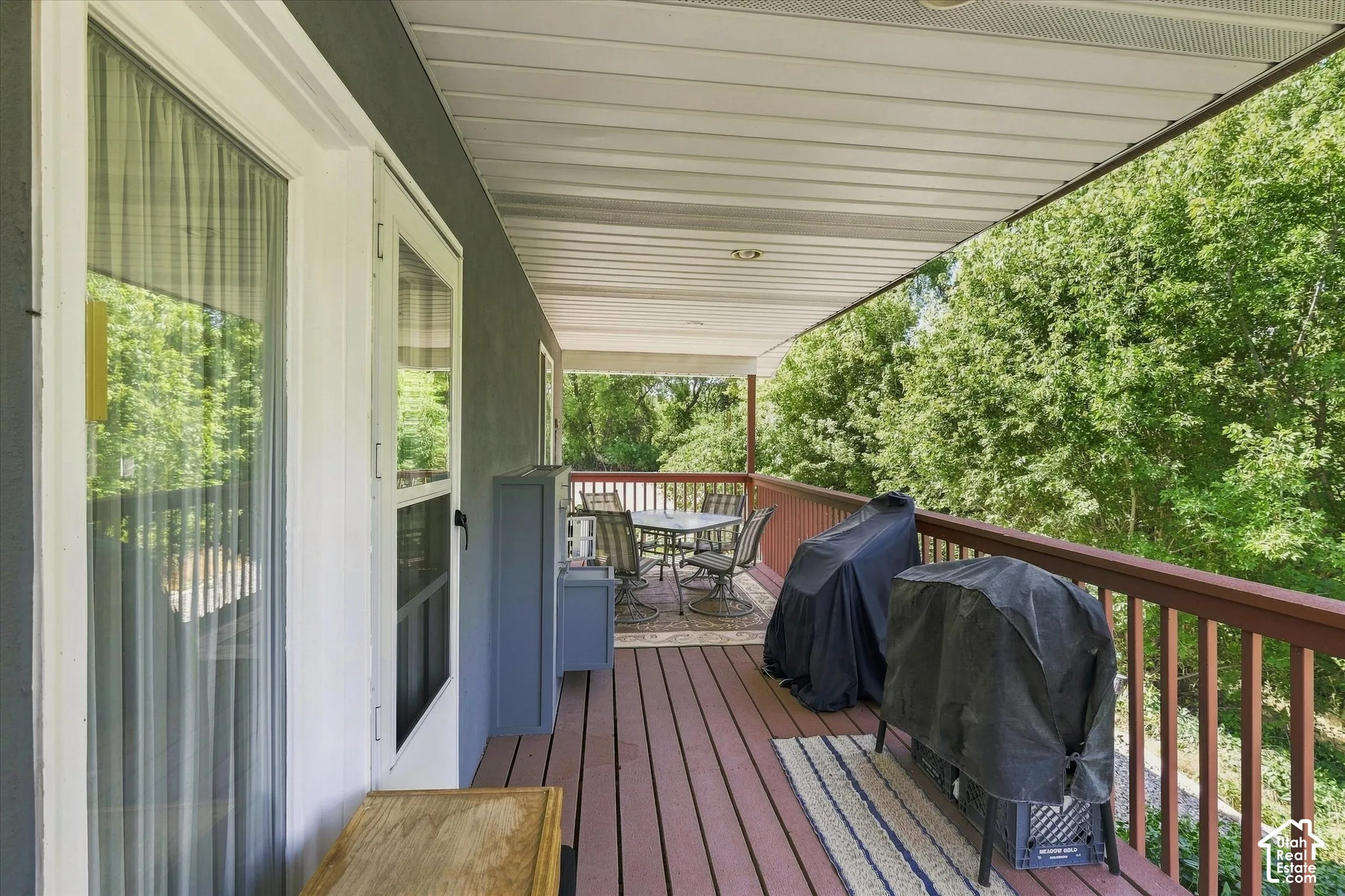 Expansive covered outdoor deck featuring wood-finish flooring, a wood-finish railing, and direct access to the dining room through a glass-paneled door