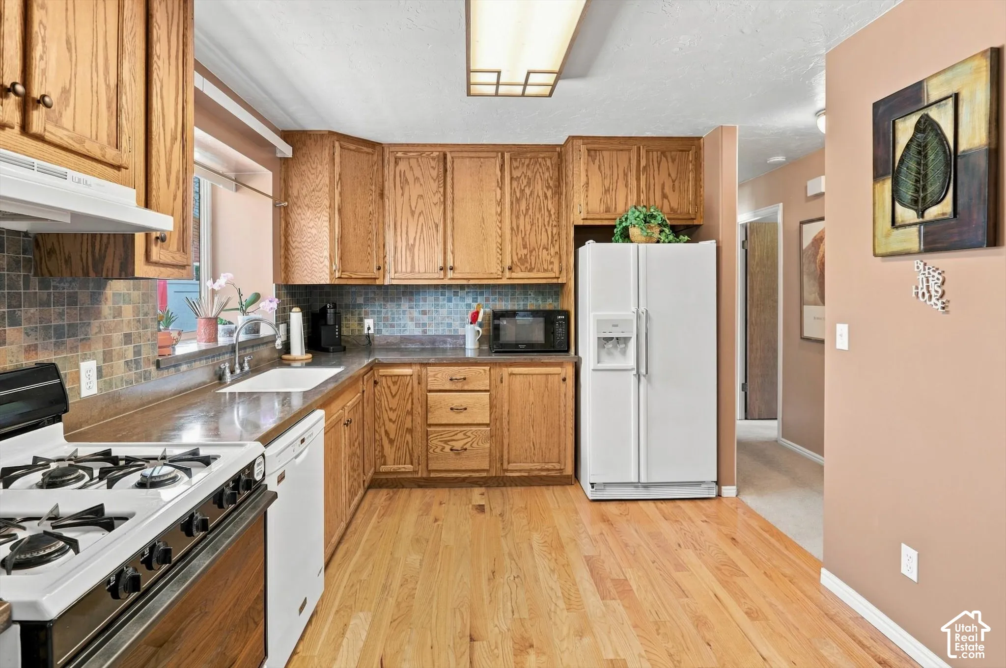 Wood-finish cabinetry paired with a tile backsplash, durable countertops, and wood-finish flooring
