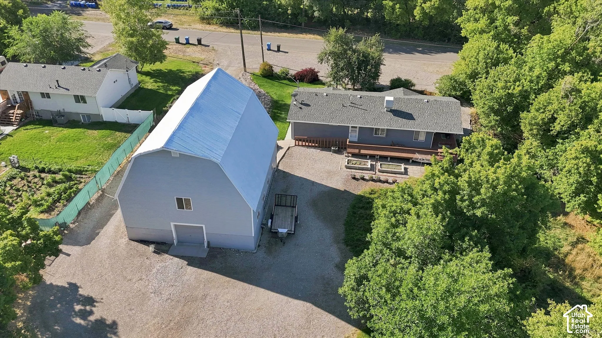 Expansive barn structure, home, yard, and surrounding mature trees
