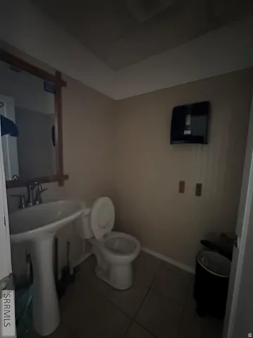 Pedestal sink with dual-handle faucet, ceramic tile flooring, and a standard toilet