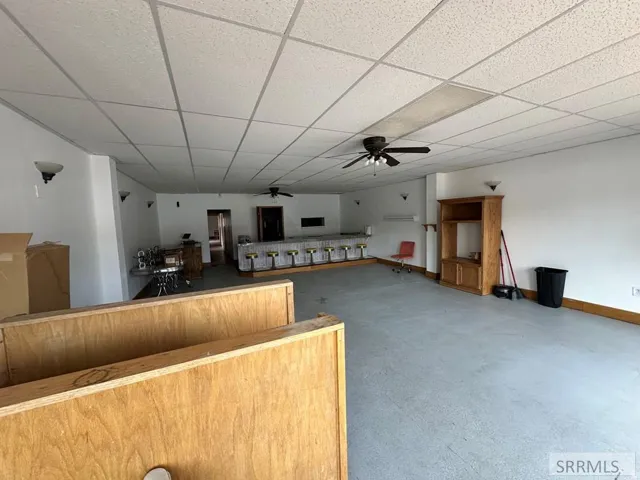Large open space featuring a built-in bar with seating, recessed ceiling, and multiple wall sconces
