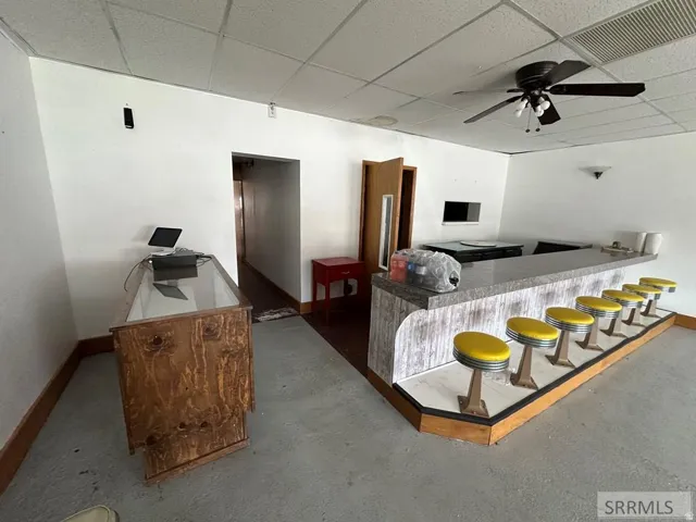 Built-in bar with counter seating, drop ceiling, and ceiling fan fixture