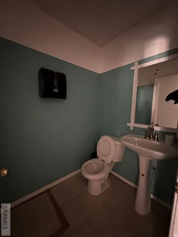 Pedestal sink, wall-mounted faucet, and tiled flooring