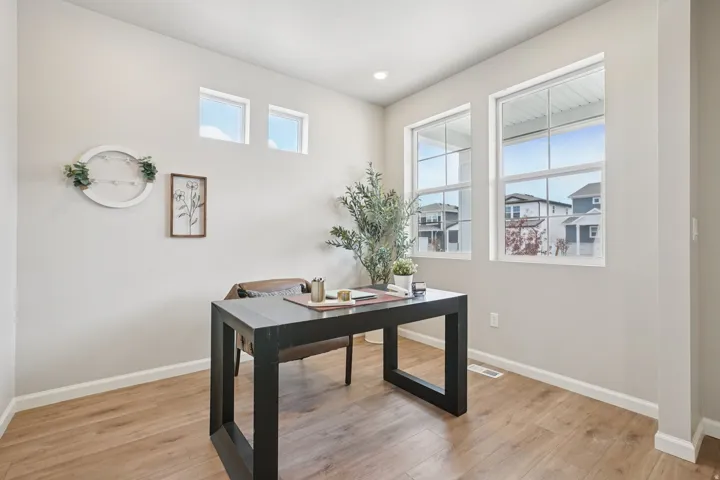 Room with light wood-finish flooring, two large multi-pane windows, two transom windows, and recessed ceiling lighting
