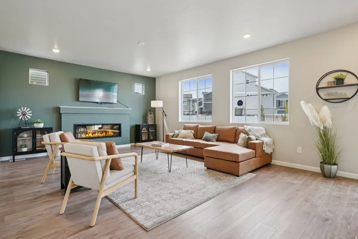 Recessed lighting, wood-finish flooring, two large windows, built-in linear fireplace, and a painted accent wall