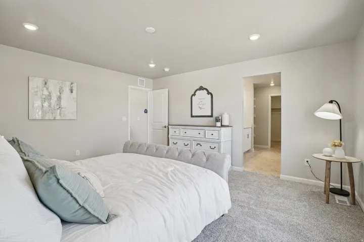 Recessed ceiling lighting, light gray wall paint, carpeting, and a white six-drawer dresser