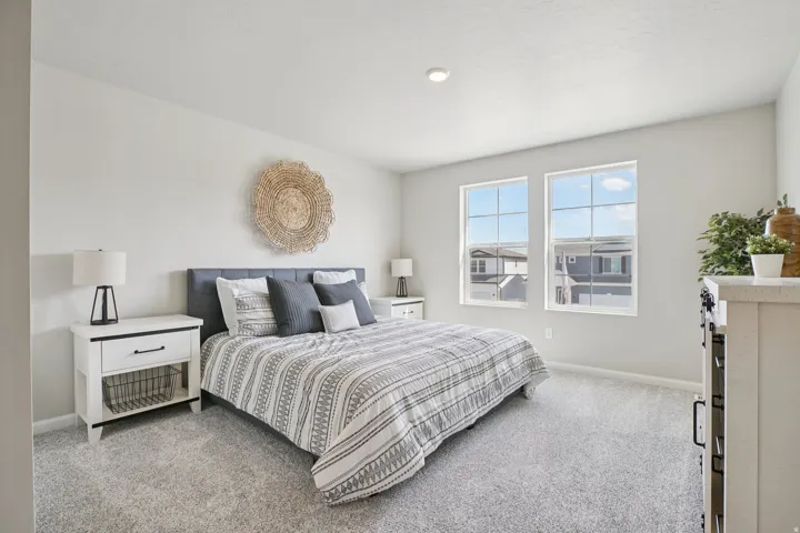 Recessed lighting, light-colored walls, two gridded windows, and soft gray carpet flooring