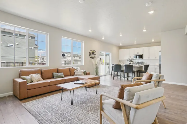 Recessed lighting, wood-finish flooring, white cabinetry, stainless steel appliances, and a kitchen island with seating