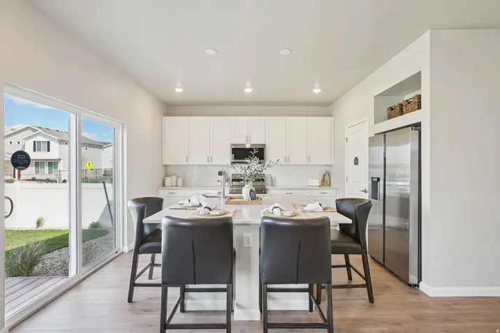 White cabinetry with stainless steel appliances, recessed lighting, and wood-finish flooring