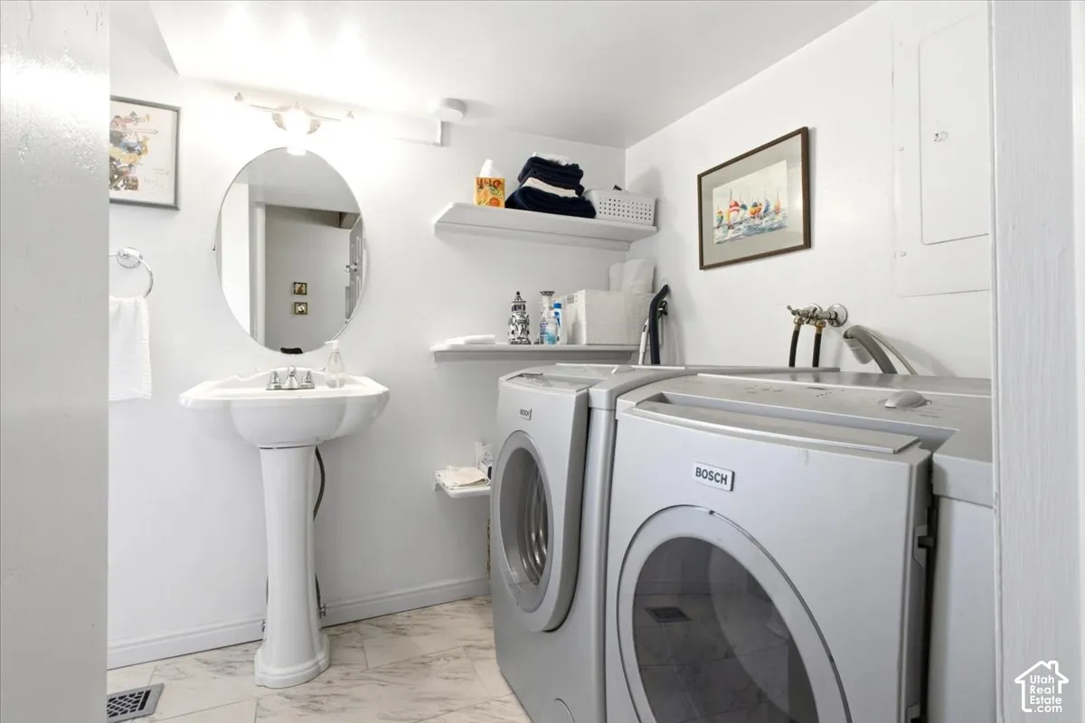White pedestal sink with a wall-mounted oval mirror and washer/dryer area.