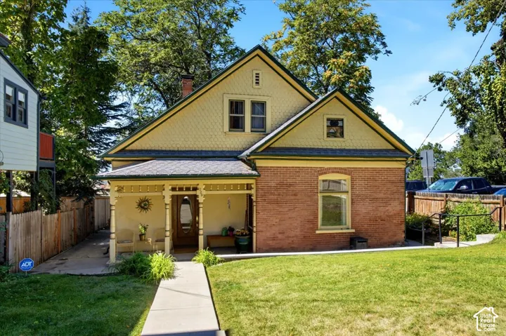 Brick and shingle exterior with a covered front porch, featuring decorative columns and a gabled roofline