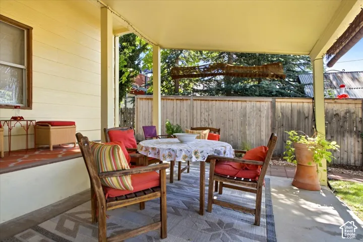 Covered patio area with concrete flooring, accented by a wood privacy fence and mature trees, faces west to see the sunsets!