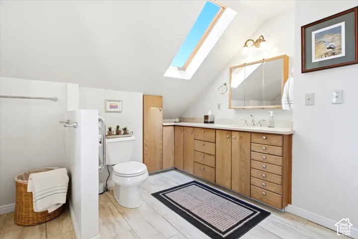 Bathroom featuring a skylight, vanity with an integrated sink, and light-toned tile flooring.