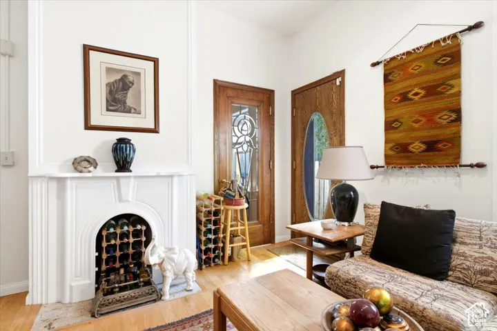 White fireplace surround with mantel, hardwood flooring, and wood doors with beveled glass inserts